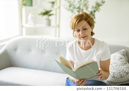 Portrait of smiling middle aged woman reading book at home 131706588