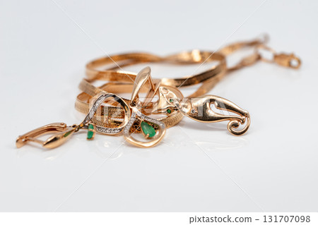 Luxurious jewelry: gold earrings with emeralds, a bracelet, a chain and a pendant in the form of a cat 131707098