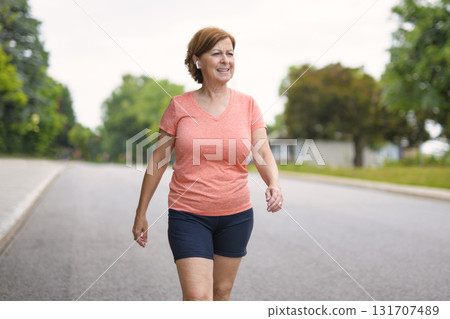 Woman fast walking outdoors with wireless headphones Woman fast walking outdoors with wireless headphones 131707489