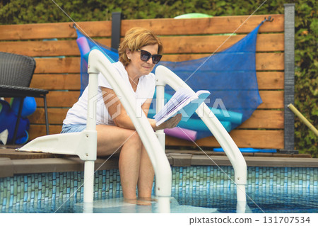 beautiful woman reading book by swimming pool with feeling relaxed beautiful woman reading book by swimming pool with feeling relaxed 131707534