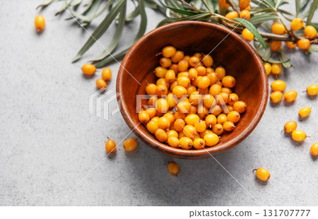Sea buckthorn berries in wooden bowl on grey background 131707777