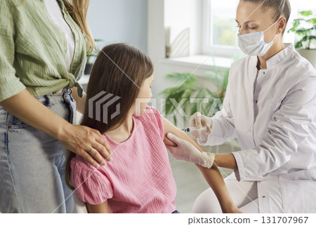 Pediatric clinic vaccination: doctor gives child an injection while parent helps 131707967