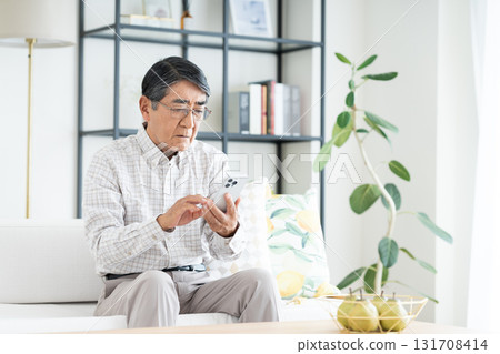 Senior man using a smartphone in the living room Senior man using a smartphone in the living room 131708414