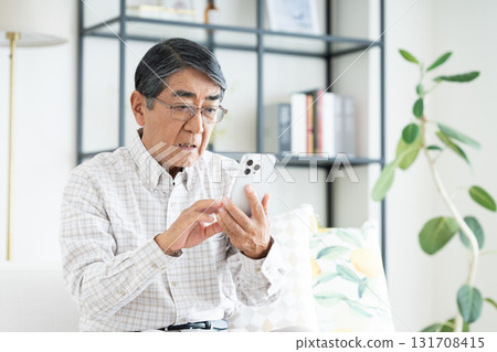 Senior man using a smartphone in the living room 131708415
