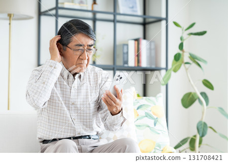 Senior man using a smartphone in the living room Senior man using a smartphone in the living room 131708421