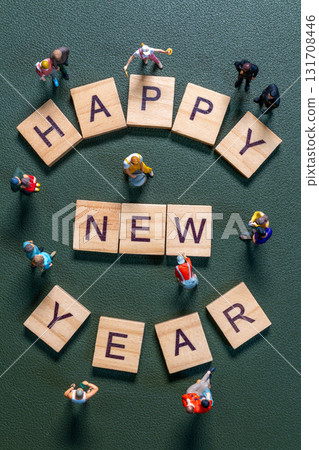 Miniature figurines surrounding wooden letter tiles forming the phrase Happy New Year 131708446