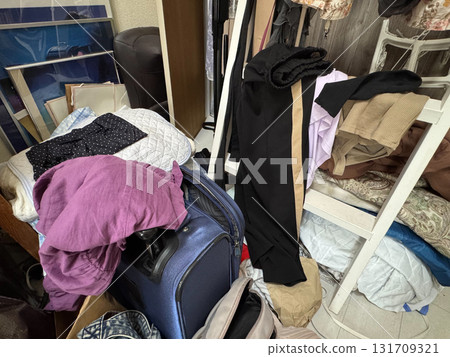 A messy woman's room - clothes, carry-on bags, etc. 131709321