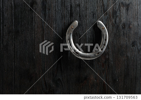 Old horseshoe on a black wooden background. 131709563
