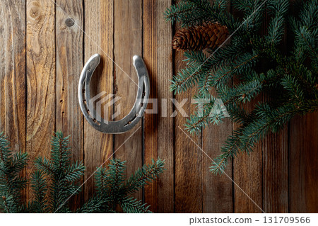 Old horseshoe and spruce branches on a wooden background. Old horseshoe and spruce branches on a wooden background. 131709566