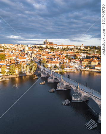 Morning light illuminates the historic Charles Bridge and Prague Castle. The serene Vltava River reflects the beauty of Old Town, creating a picturesque scene in Prague. 131709720