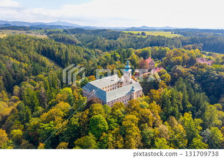 Lemberk castle stands majestically above the vibrant landscape. Surrounded by lush forests and hills, this chateau showcases beautiful medieval architecture under a clear sky. 131709738