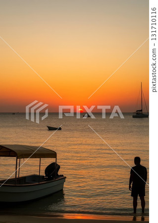 ropical beach sunset with boats and a human silhouette on the calm sea horizon at golden hour ropical beach sunset with boats and a human silhouette on the calm sea horizon at golden hour 131710116
