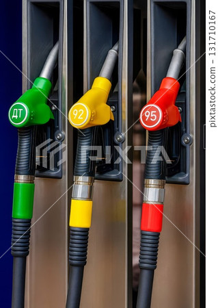 Fuel pump nozzles at gas station with green diesel and yellow 92 and red 95 octane options 131710167
