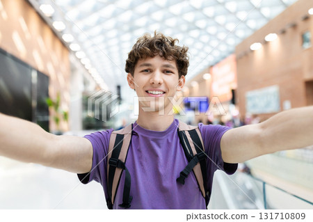 Young Caucasian man smiling with arms open for selfie at airport Young Caucasian man smiling with arms open for selfie at airport 131710809