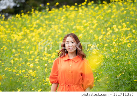 A woman standing in front of a rape field 131711355