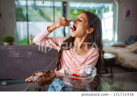 Young girl enjoying eating strawberry with chocolate at home Young girl enjoying eating strawberry with chocolate at home 131711436