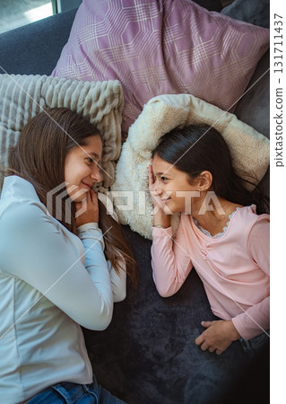 Sisters communicating on sofa in cozy home environment 131711437