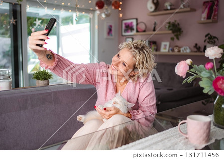 Woman taking selfie with her pet cat at home Woman taking selfie with her pet cat at home 131711456