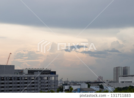a cityscape featuring various modern buildings and other structures, including a prominent construction crane. The atmosphere appears gloomy due to the heavy, overcast clouds that fill the sky, which a cityscape featuring various modern buildings and other structures, including a prominent construction crane. The atmosphere appears gloomy due to the heavy, overcast clouds that fill the sky, which 131711883