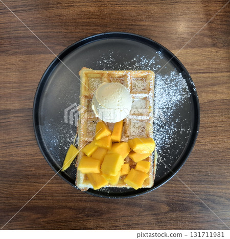 Belgian waffle with fresh mango and vanilla ice cream 131711981