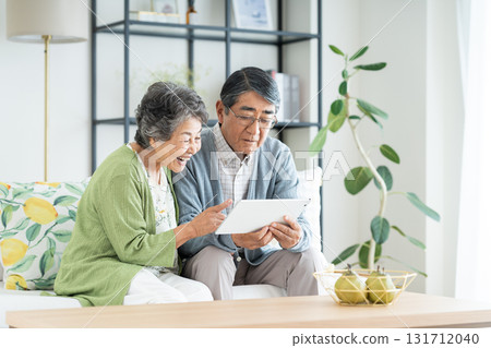 一對老年夫婦在客廳看平板電腦 一對老年夫婦在客廳看平板電腦 131712040