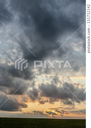Dramatic sunset sky filled with clouds over a vast field at dusk capturing vibrant colors and natural beauty 131712142