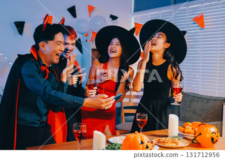Joyful office Halloween party with coworkers in costumes, celebrating with drinks and laughter, fostering teamwork and festive spirit 131712956