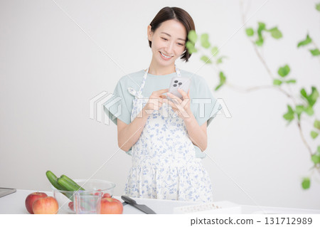 Image of a housewife searching for a recipe in the kitchen Image of a housewife searching for a recipe in the kitchen 131712989