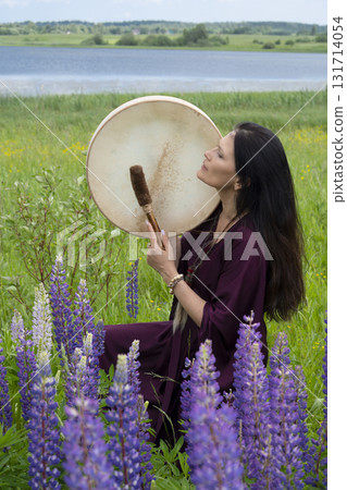 Shaman woman drumming among blooming flowers 131714054