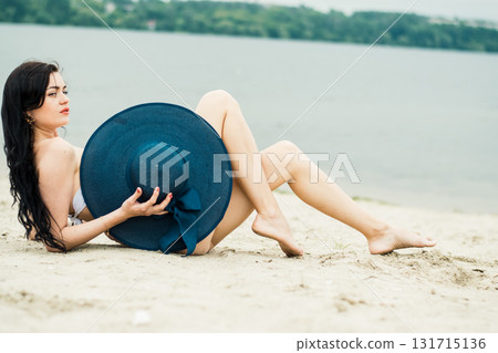 A young woman is sitting on the warm beach sand, enjoying the silence A young woman is sitting on the warm beach sand, enjoying the silence 131715136