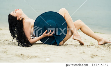 A young woman is sitting on the warm beach sand, enjoying the silence A young woman is sitting on the warm beach sand, enjoying the silence 131715137