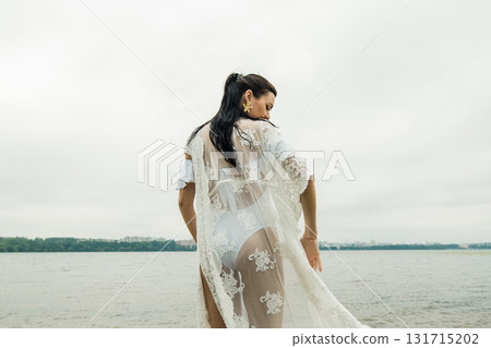 A young woman poses by the lake against the background of water A young woman poses by the lake against the background of water 131715202