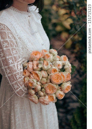 Bouquet in female hands. Bunch of Living Coral roses. 131715223