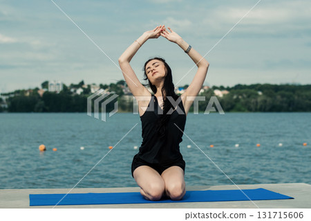 A girl practicing yoga on the shore of a lake A girl practicing yoga on the shore of a lake 131715606