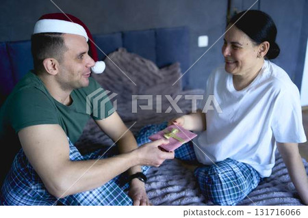 senior woman and young man exchange New Year's gifts, gift certificates, celebration at home 131716066