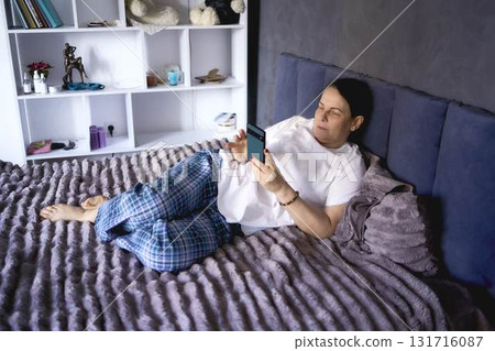 a senior woman chatting on the phone in bed a senior woman chatting on the phone in bed 131716087