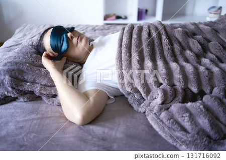 a senior woman in silk eye mask sleeping under heavy blanket 131716092