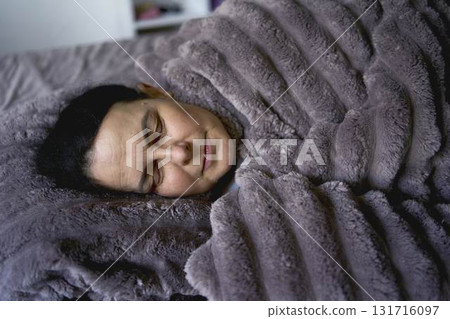 a senior woman sleeping under a weighted blanket 131716097