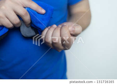 A man suffers from palmar hyperhidrosis. He wipes his sweaty palms due to excessive sweating. Treatment of hyperhidrosis with botulinum toxin injection into the hand. A man suffers from palmar hyperhidrosis. He wipes his sweaty palms due to excessive sweating. Treatment of hyperhidrosis with botulinum toxin injection into the hand. 131716165
