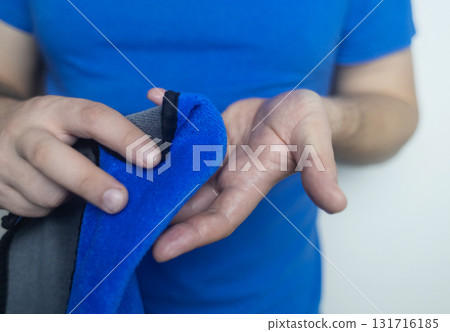 A man suffers from palmar hyperhidrosis. He wipes his sweaty palms due to excessive sweating. Treatment of hyperhidrosis with botulinum toxin injection into the hand. 131716185