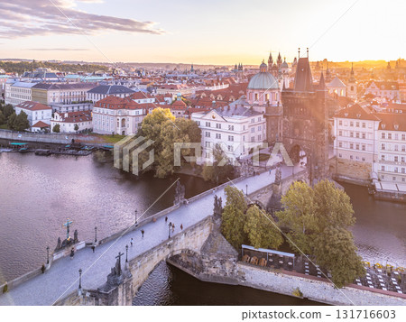 The Old Town Bridge Tower stands tall at sunrise, overlooking the Charles Bridge. Visitors stroll along the bridge, enjoying the beautiful scenery of Prague and the Vltava River. The Old Town Bridge Tower stands tall at sunrise, overlooking the Charles Bridge. Visitors stroll along the bridge, enjoying the beautiful scenery of Prague and the Vltava River. 131716603