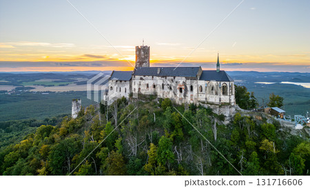 Bezdez Castle, a medieval ruin perched on a hill, offers a stunning aerial view during summer dusk. The old tower stands tall against a vibrant sunset sky, highlighting its historical significance. 131716606