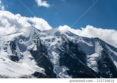 Piz Palu showcases its stunning glacier-covered peaks under a clear blue sky. This iconic mountain in the Bernina range resembles a striking natural fortress in Switzerland. 131716618