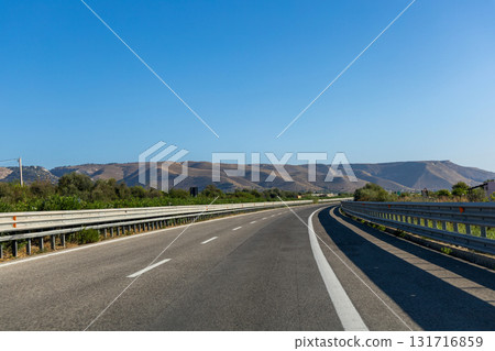 Scenic highway surrounded by hills under clear sky Scenic highway surrounded by hills under clear sky 131716859