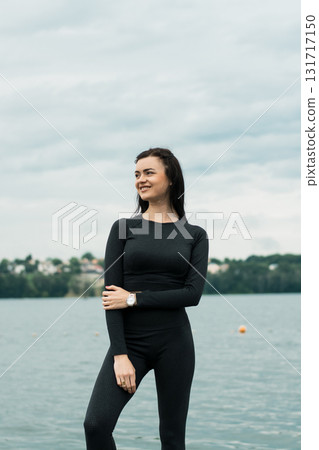 A beautiful woman with an athletic build poses against the backdrop of the water's surface A beautiful woman with an athletic build poses against the backdrop of the water's surface 131717150