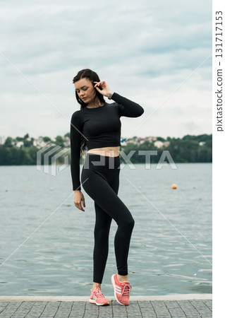 A young woman with an athletic build stands by the lake 131717153