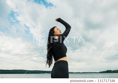 An athlete with an athletic build poses in black clothing against the backdrop of a natural landscape An athlete with an athletic build poses in black clothing against the backdrop of a natural landscape 131717186