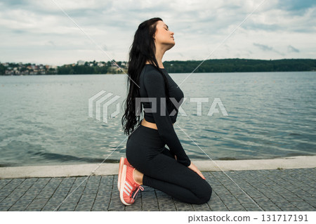 A tall athlete is doing Pilates on the lake shore A tall athlete is doing Pilates on the lake shore 131717191