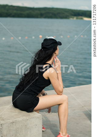 An athlete with a toned figure is sitting by the clear water An athlete with a toned figure is sitting by the clear water 131717206