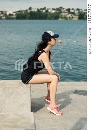 An athlete with a toned figure is sitting by the clear water An athlete with a toned figure is sitting by the clear water 131717207